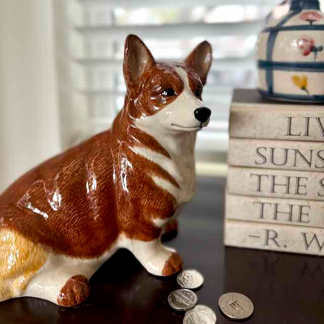 Corgi dog-shaped piggy bank with coins on a surface