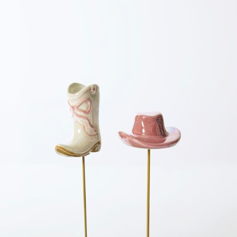 Ceramic cowboy boot and hat on sticks against a white background