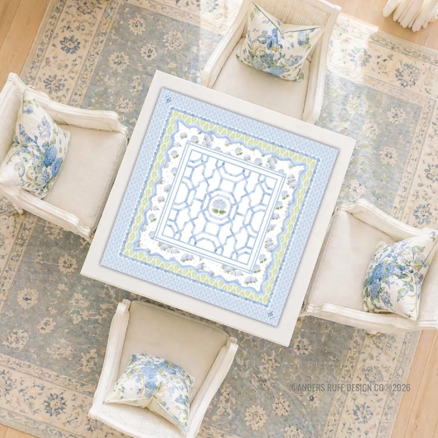 Decorative rug with a geometric pattern on a wooden floor, surrounded by floral-patterned cushions.