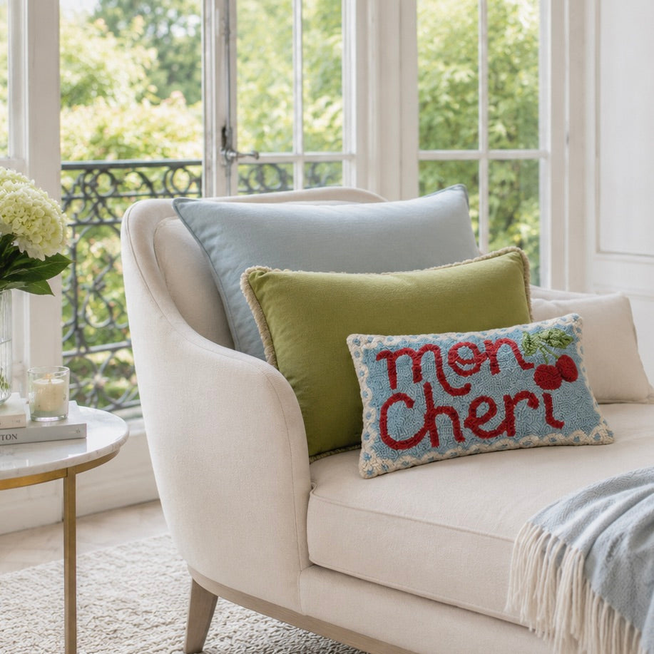 Beige armchair with decorative pillows and a 'mon cheri' pillow in a bright living room.