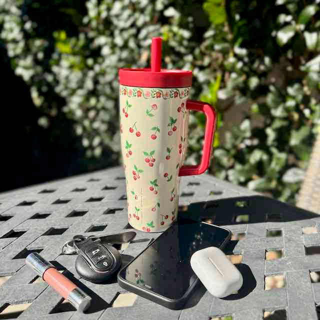 Travel mug with cherry pattern on a table outdoors