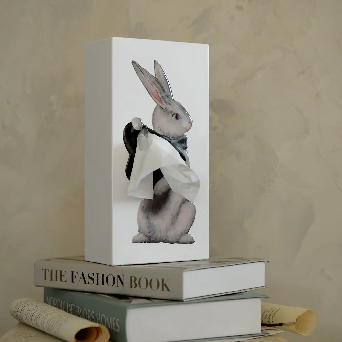 White box with a rabbit illustration on top of books against a beige background