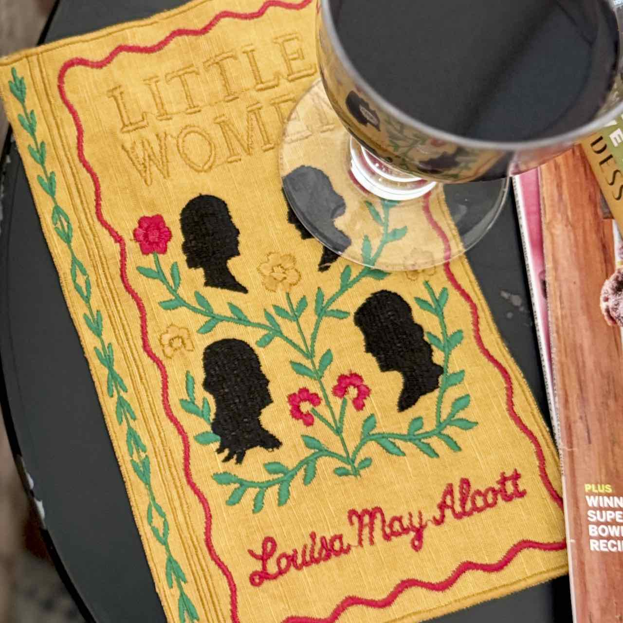 Book cover of 'Little Women' by Louisa May Alcott with a silhouette design and a cup on top.
