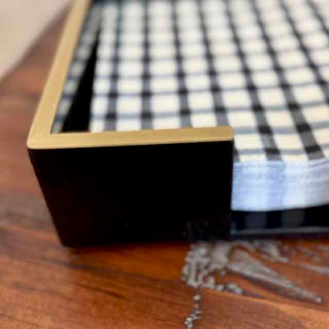 Close-up of a black and white checkered tablecloth on a wooden surface.