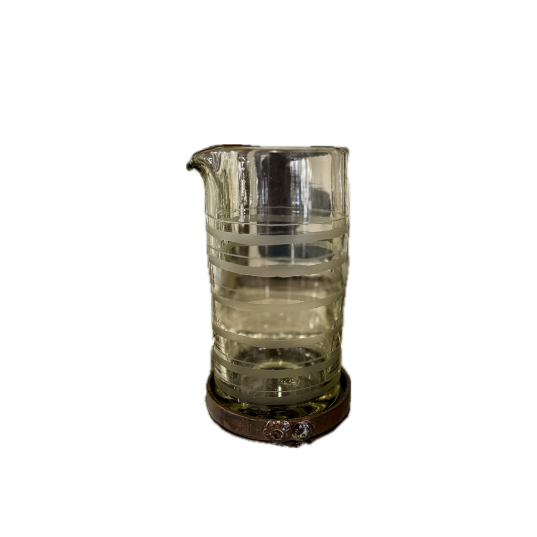 Clear glass pitcher with wooden base on a white background