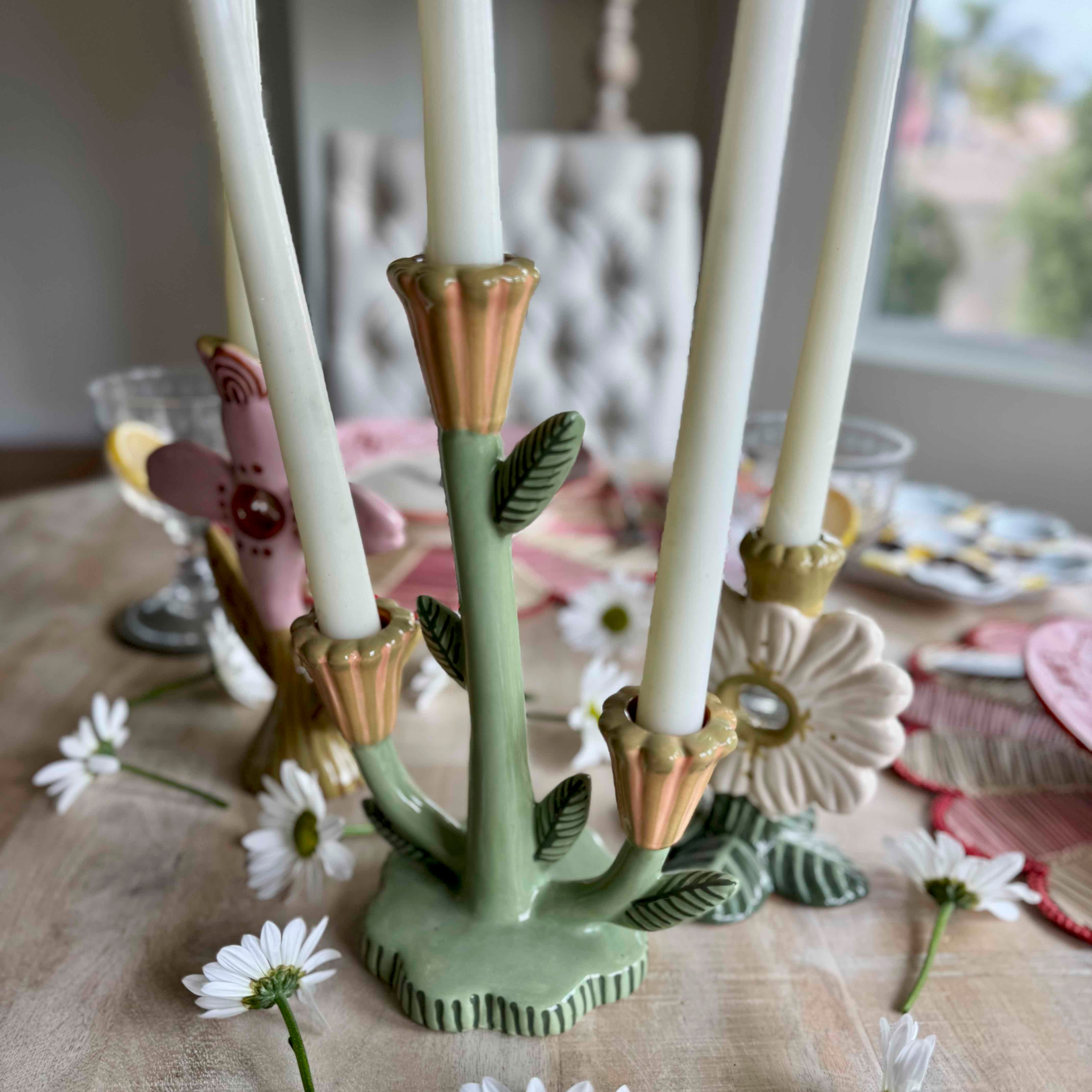 Decorative candle holder with floral design on a table with flowers and a blurred background