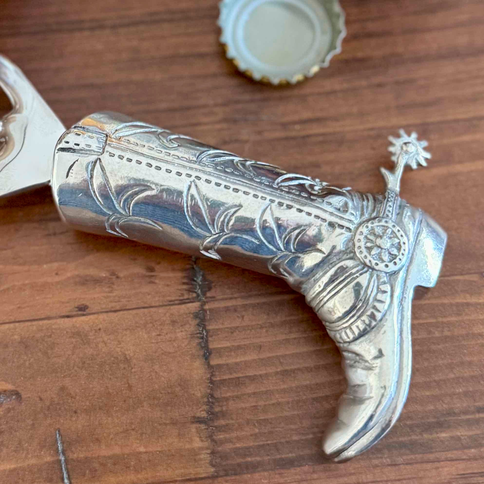 Decorative silver boot with intricate designs on a wooden surface