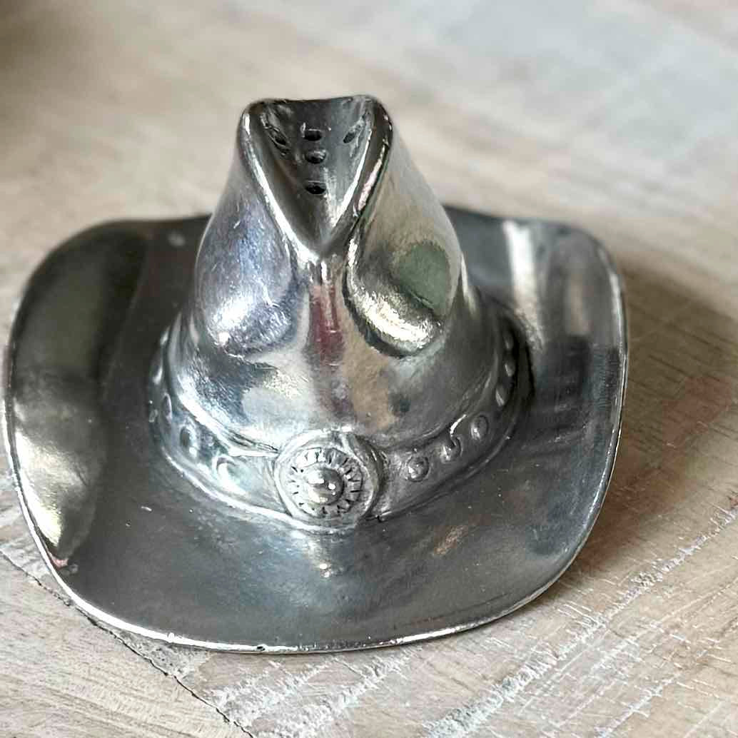 Silver cowboy hat-shaped object on a wooden surface