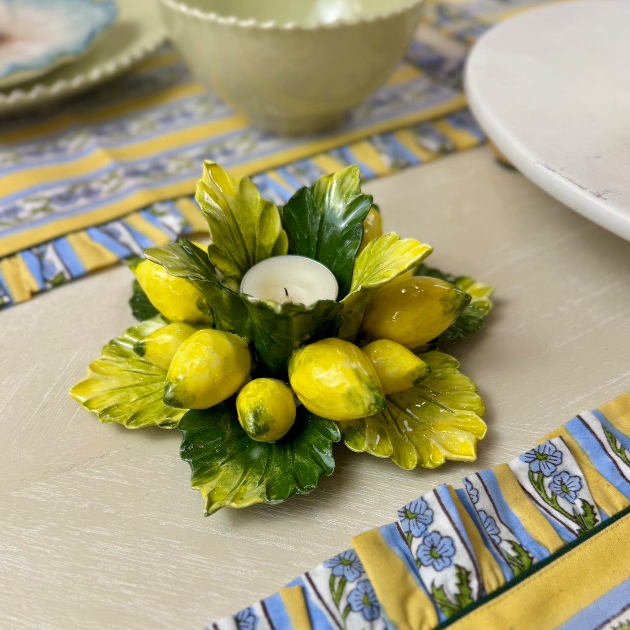 Decorative yellow and green ceramic item on a table with a colorful placemat.