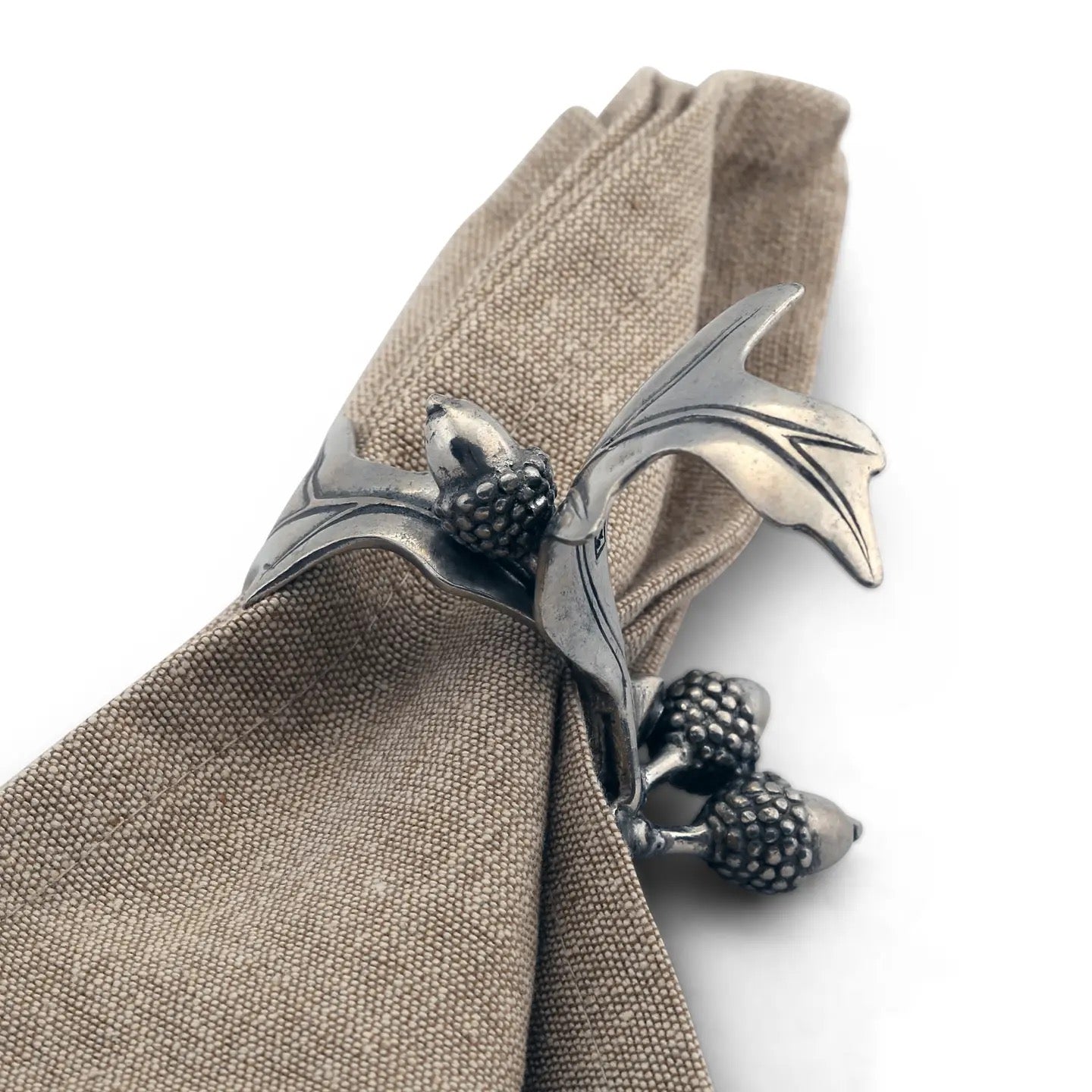 Silver napkin ring shaped like a dolphin on a beige napkin against a white background