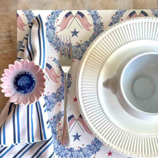 Dinner setting with a decorative placemat featuring American flags, a white plate, and cutlery.