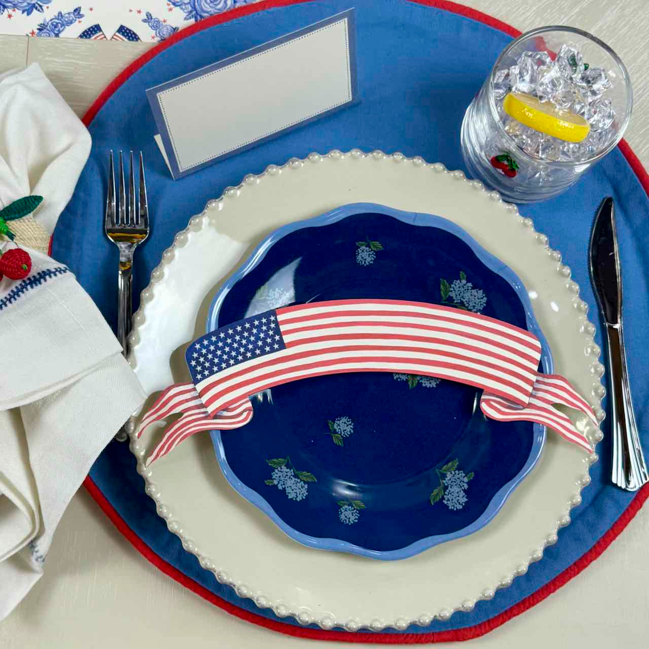 Dinner setting with a blue plate featuring an American flag design, on a matching blue placemat.
