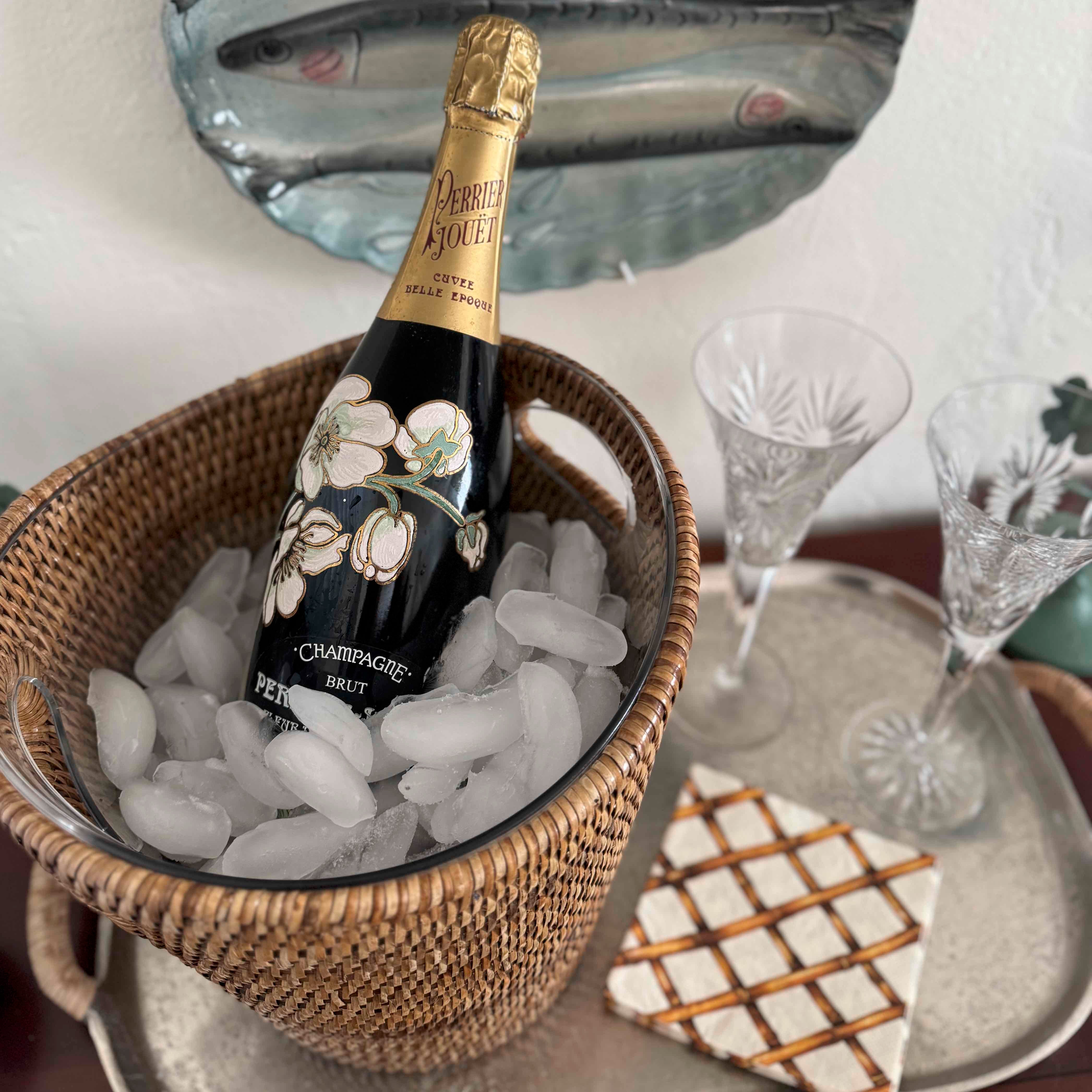 Bottle of champagne in a basket of ice with glasses on a tray