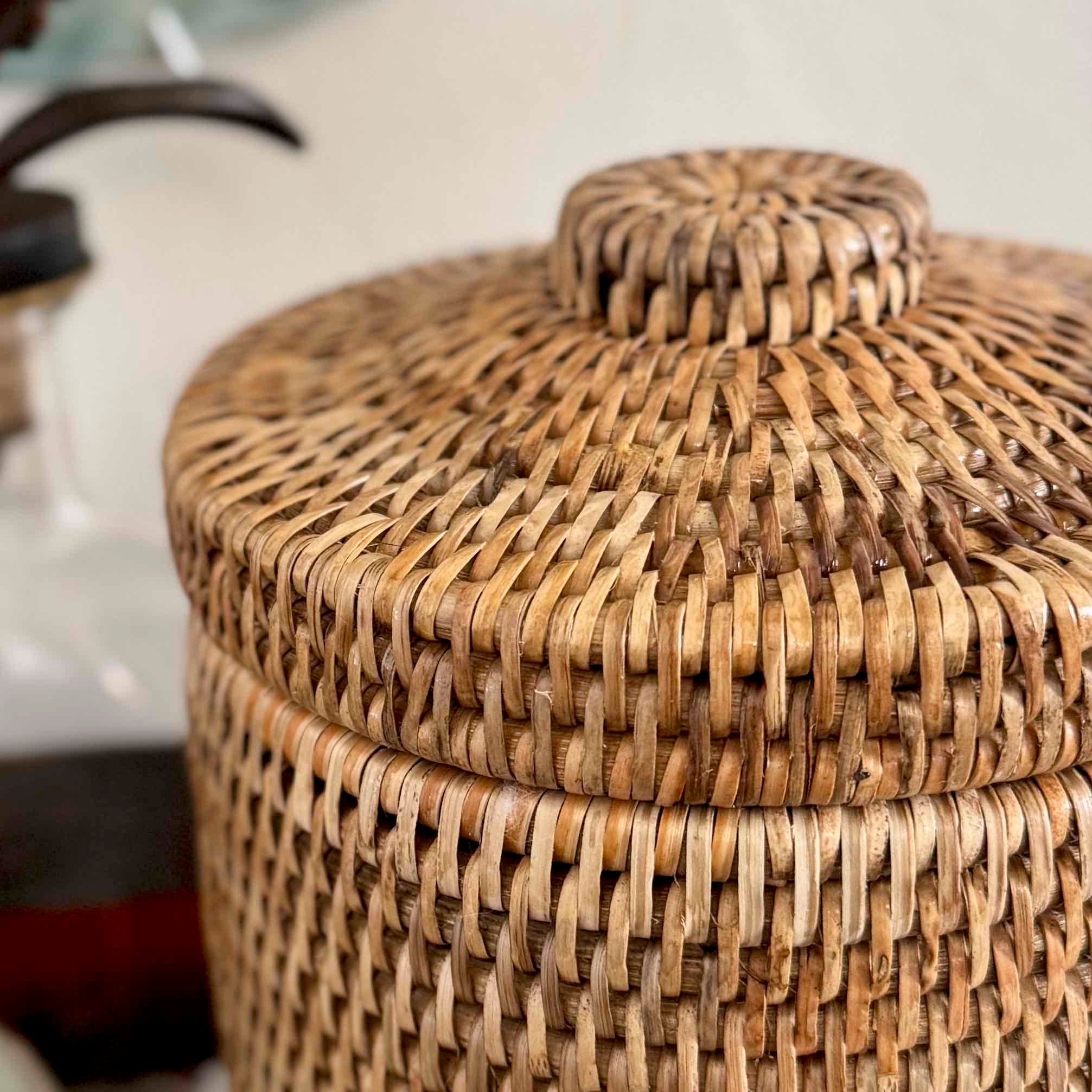 Woven rattan storage basket with a lid on a blurred background