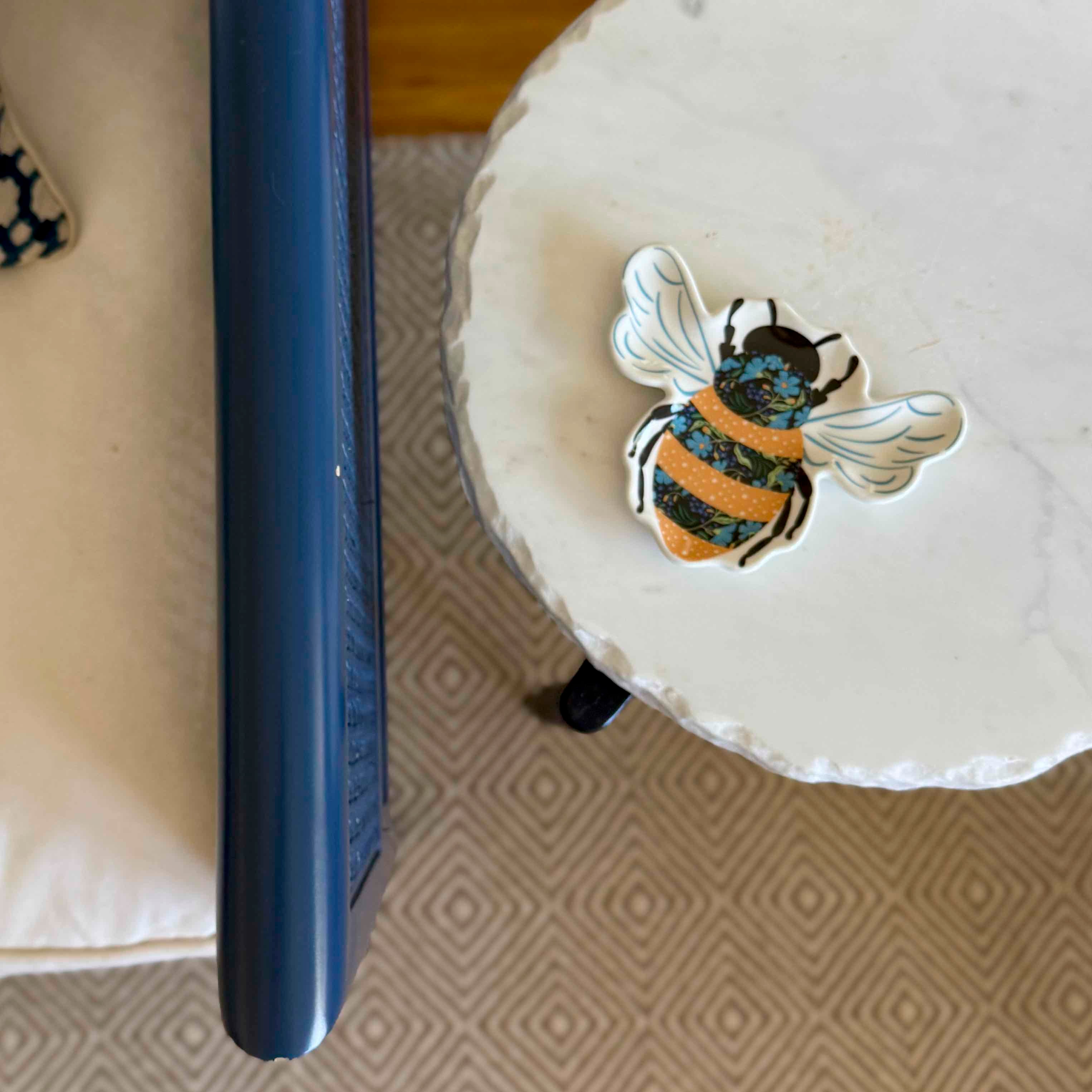 Decorative bee sticker on a white surface with a blue object next to it.