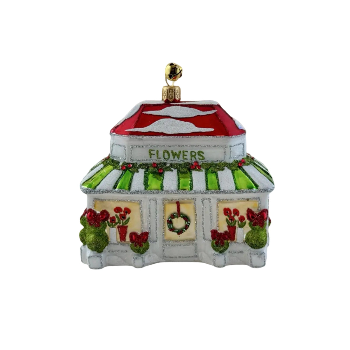 A decorative Christmas ornament shaped like a small flower shop. The white building has a red roof, green-and-white striped awning, red flowers in windows, green holly garland, and a gold hanging loop on top.