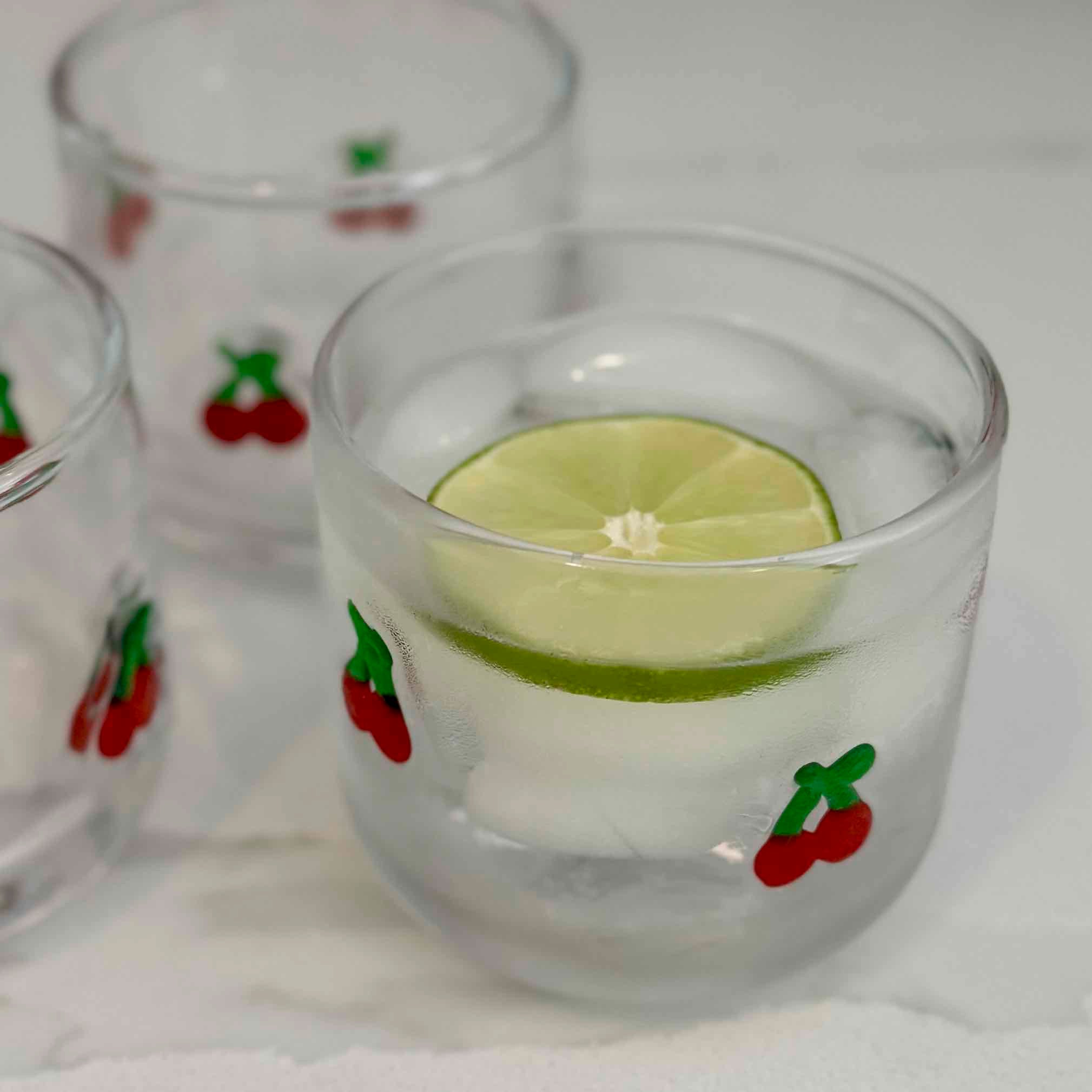 Clear glass with lime wedge and ice cubes on a white background