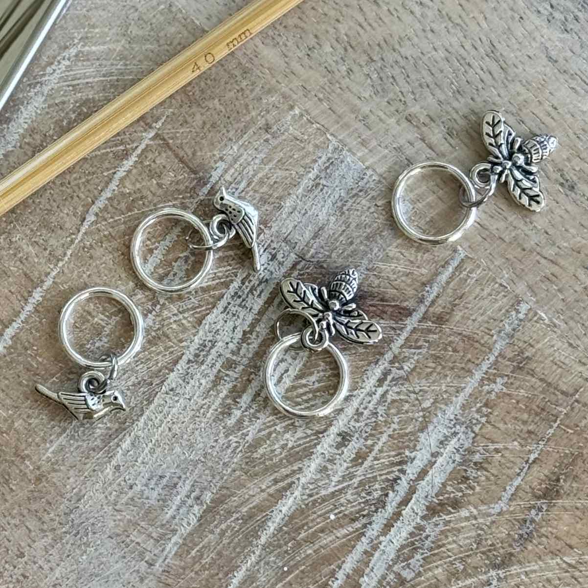 Silver charms with leaf and bird designs on a wooden surface