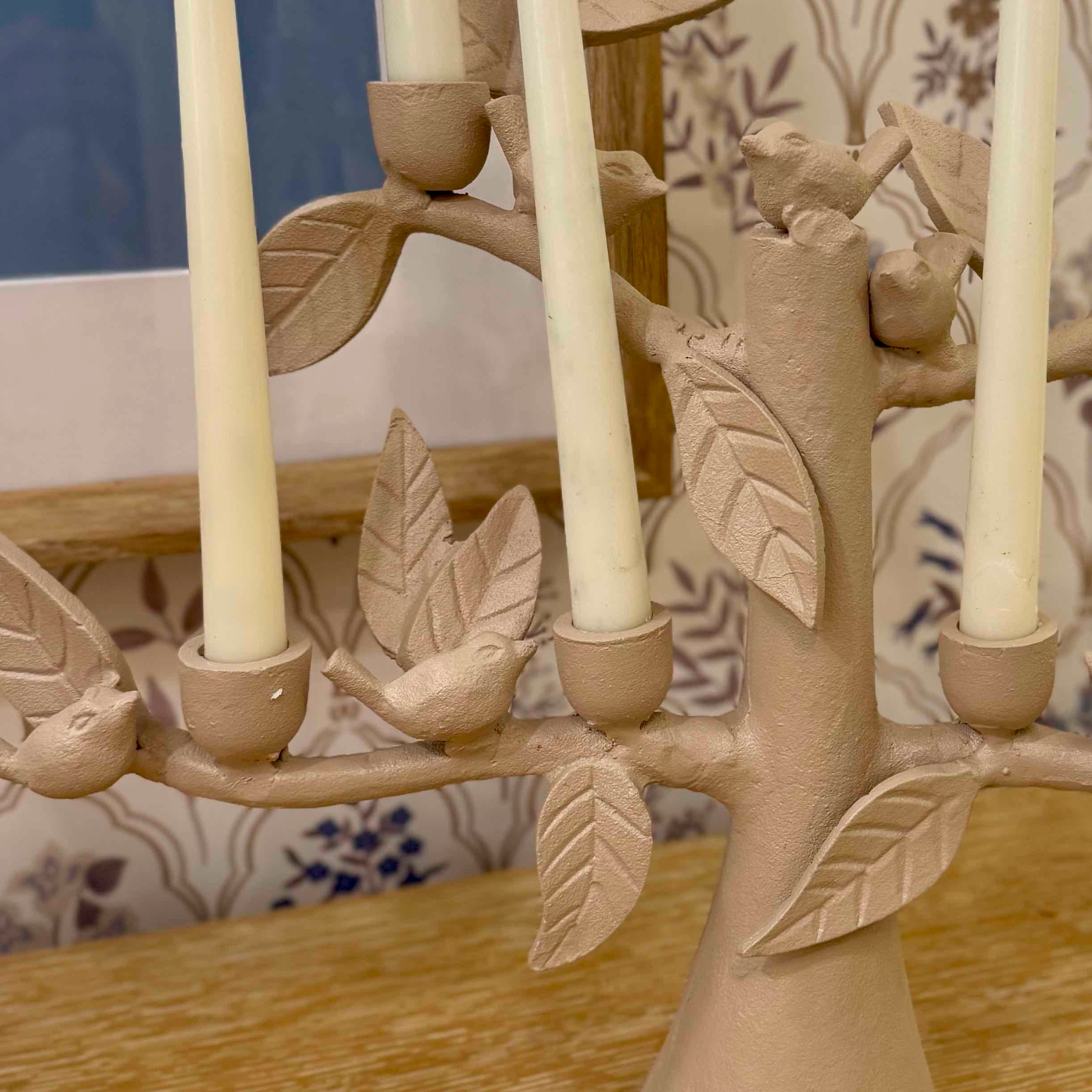 Ceramic candle holder with birds and leaves on a wooden surface