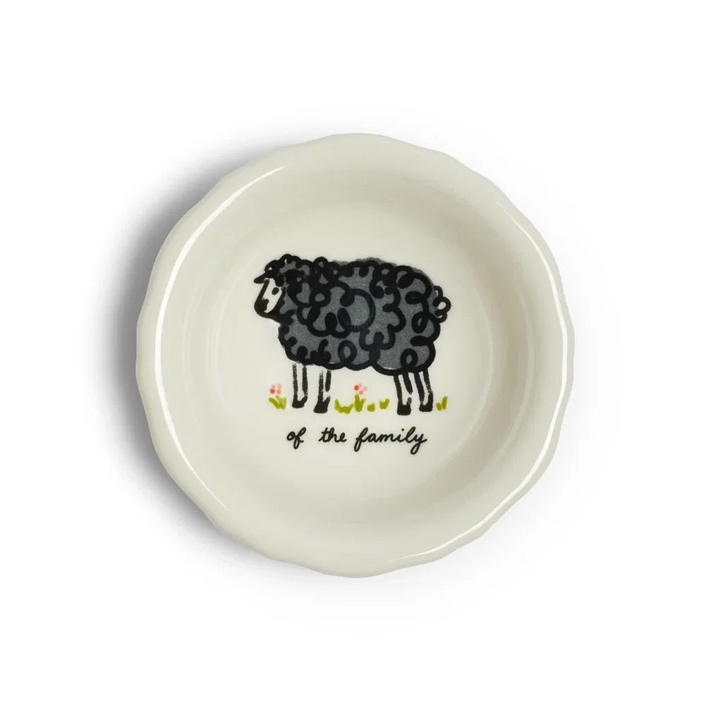A round off-white ceramic dish with a scalloped rim, featuring a black hand-drawn sheep illustration and the text 'of the family' in black script, set against a plain white background.
