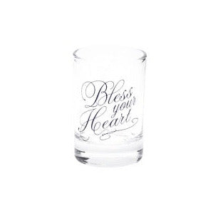 A clear glass shot glass with the phrase 'Bless your Heart' printed in elegant black cursive script on the front, set against a plain white background.