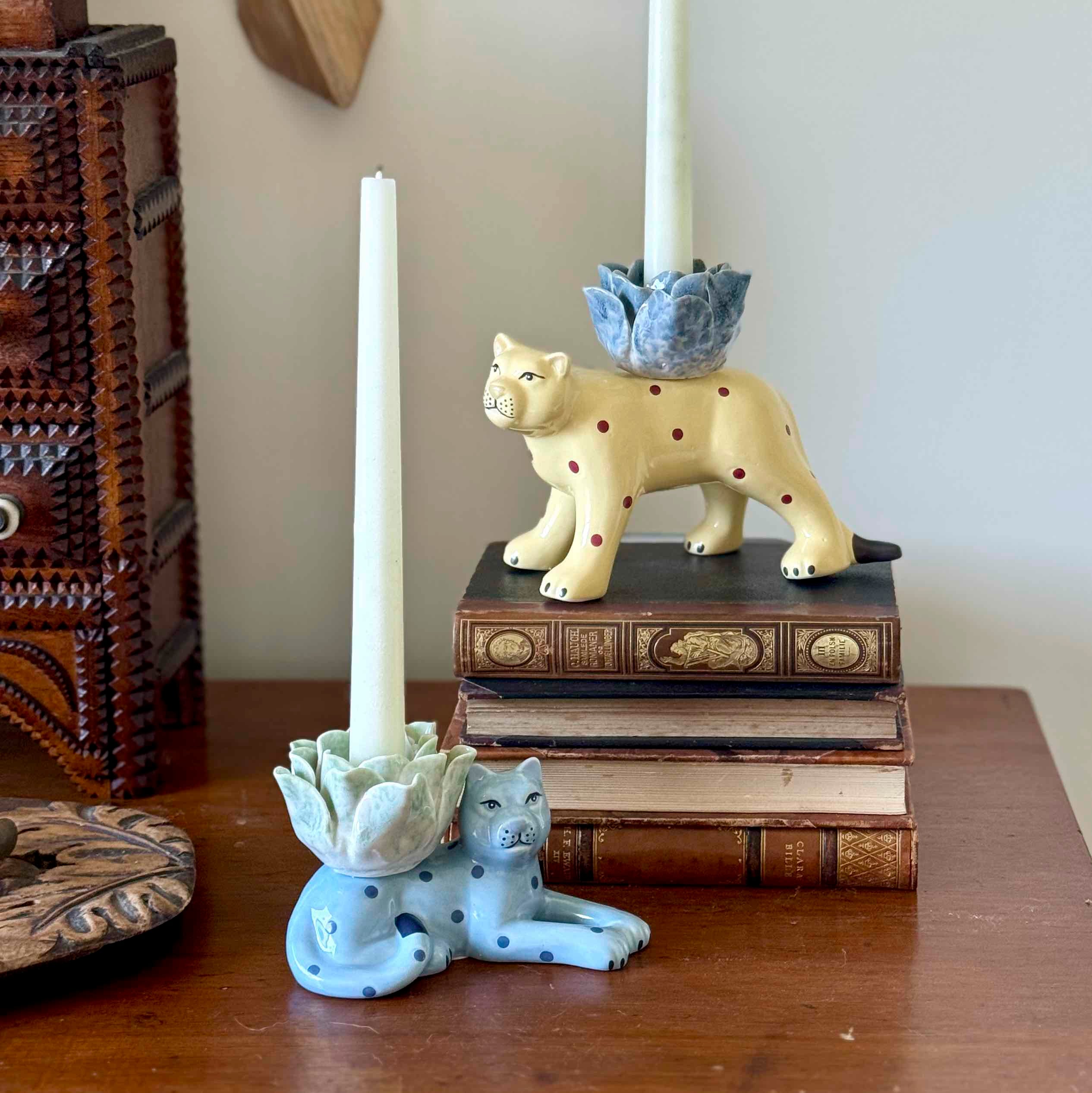 Decorative candle holders shaped like leopards on a stack of books.