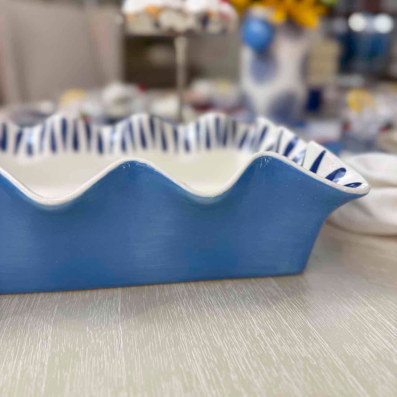 Blue and white ceramic dish with wavy edge on a neutral surface