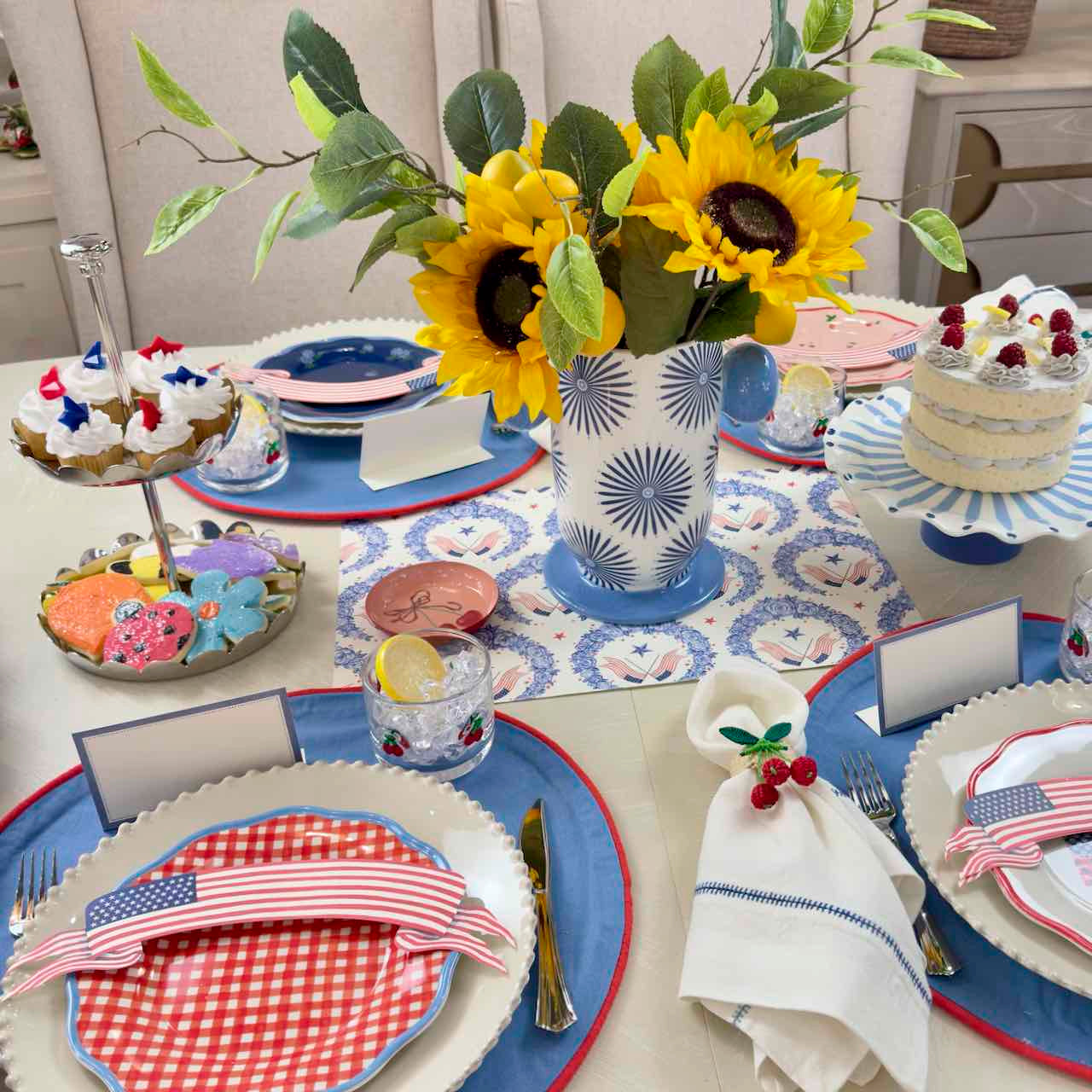 Dining table set for a celebration with plates, napkins, and a vase of sunflowers.