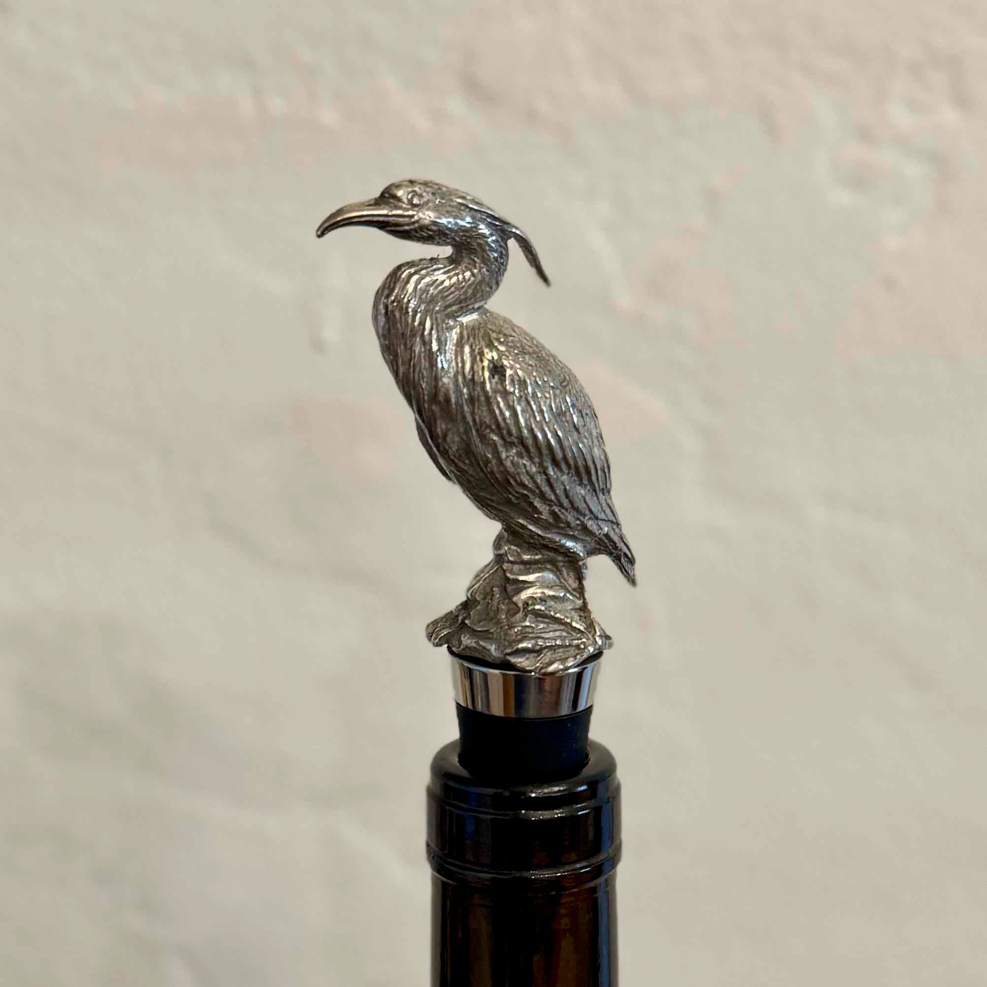Silver bird-shaped bottle stopper on a plain background