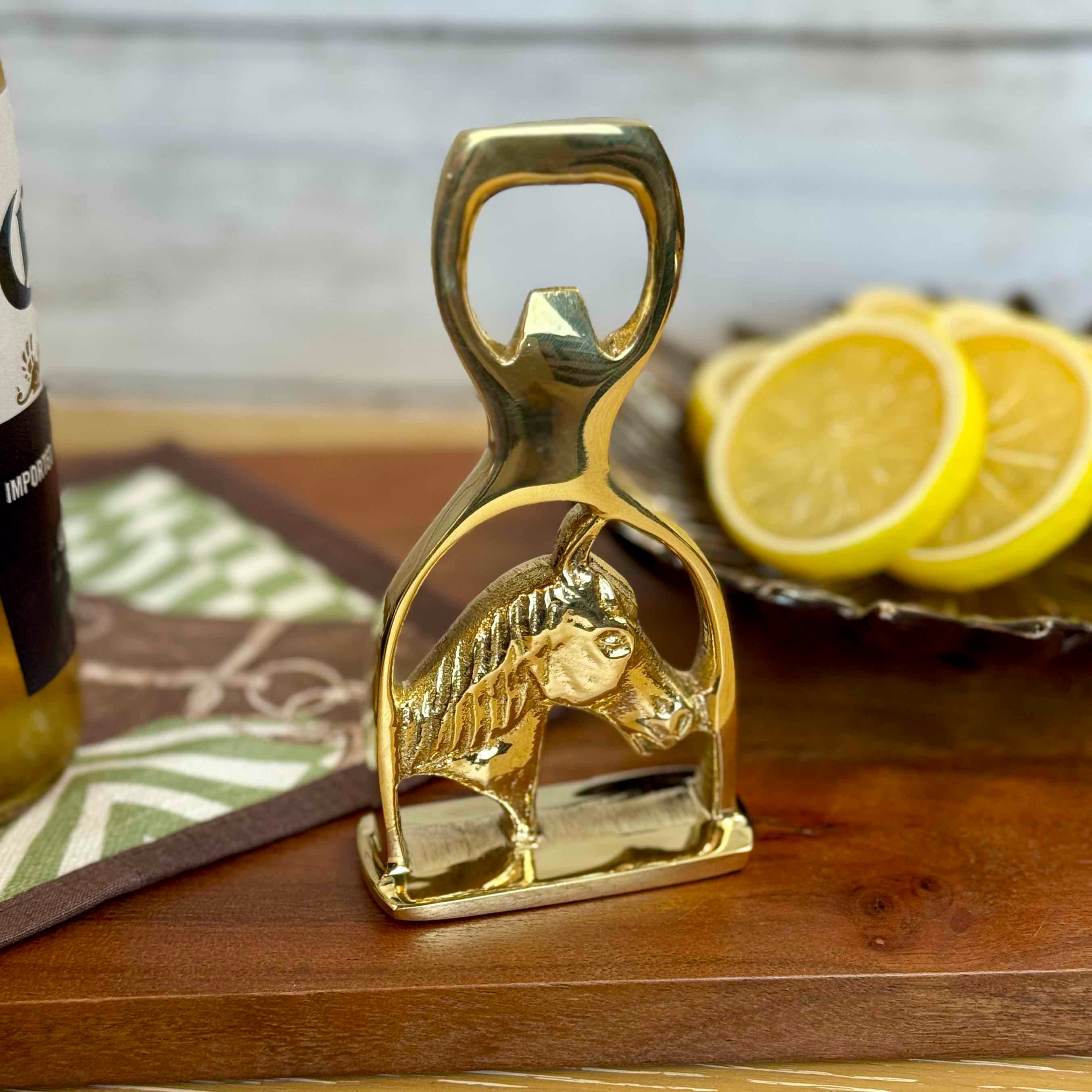 Gold horse-shaped bottle opener on a wooden surface with lemons in the background