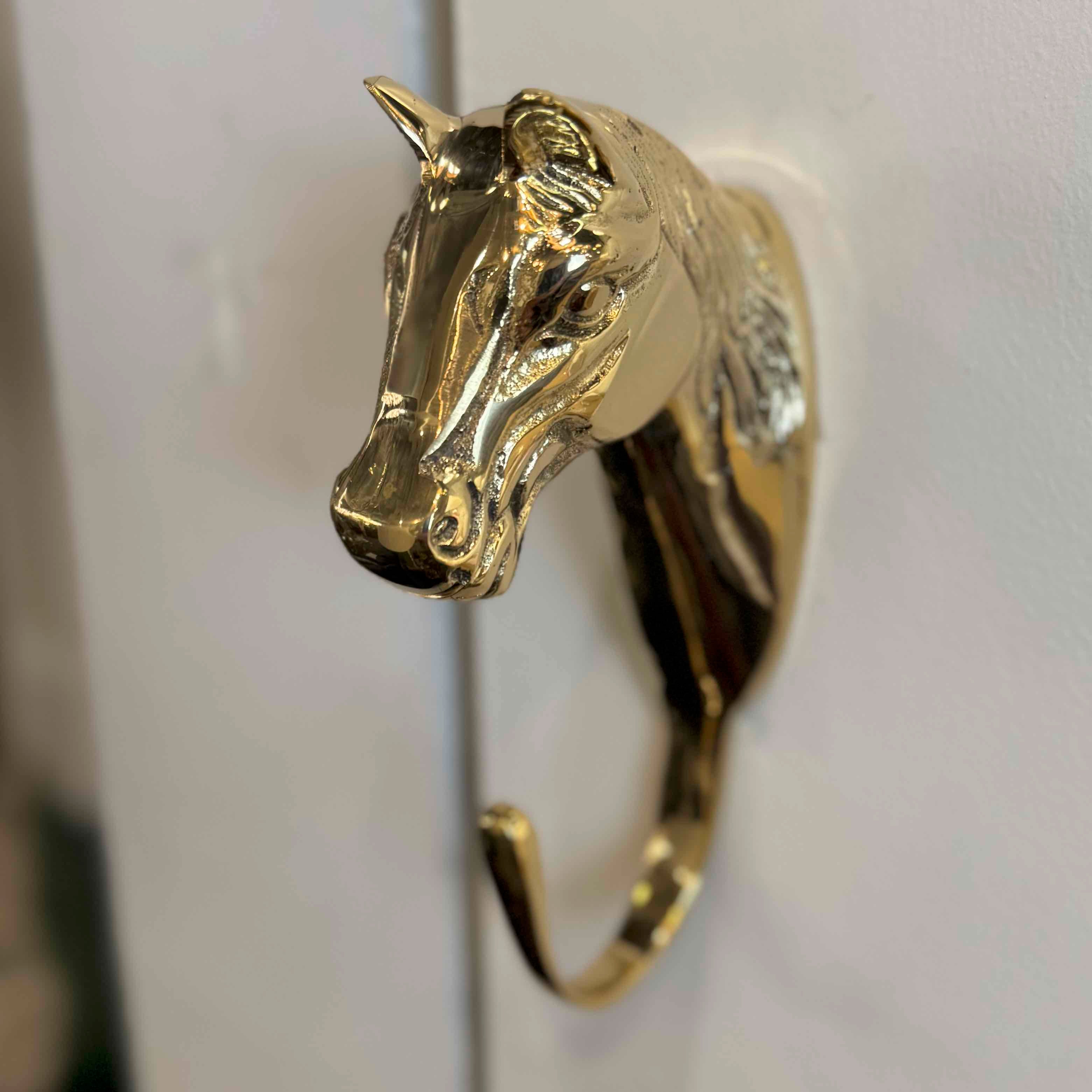 Gold horse head door knocker on a white door