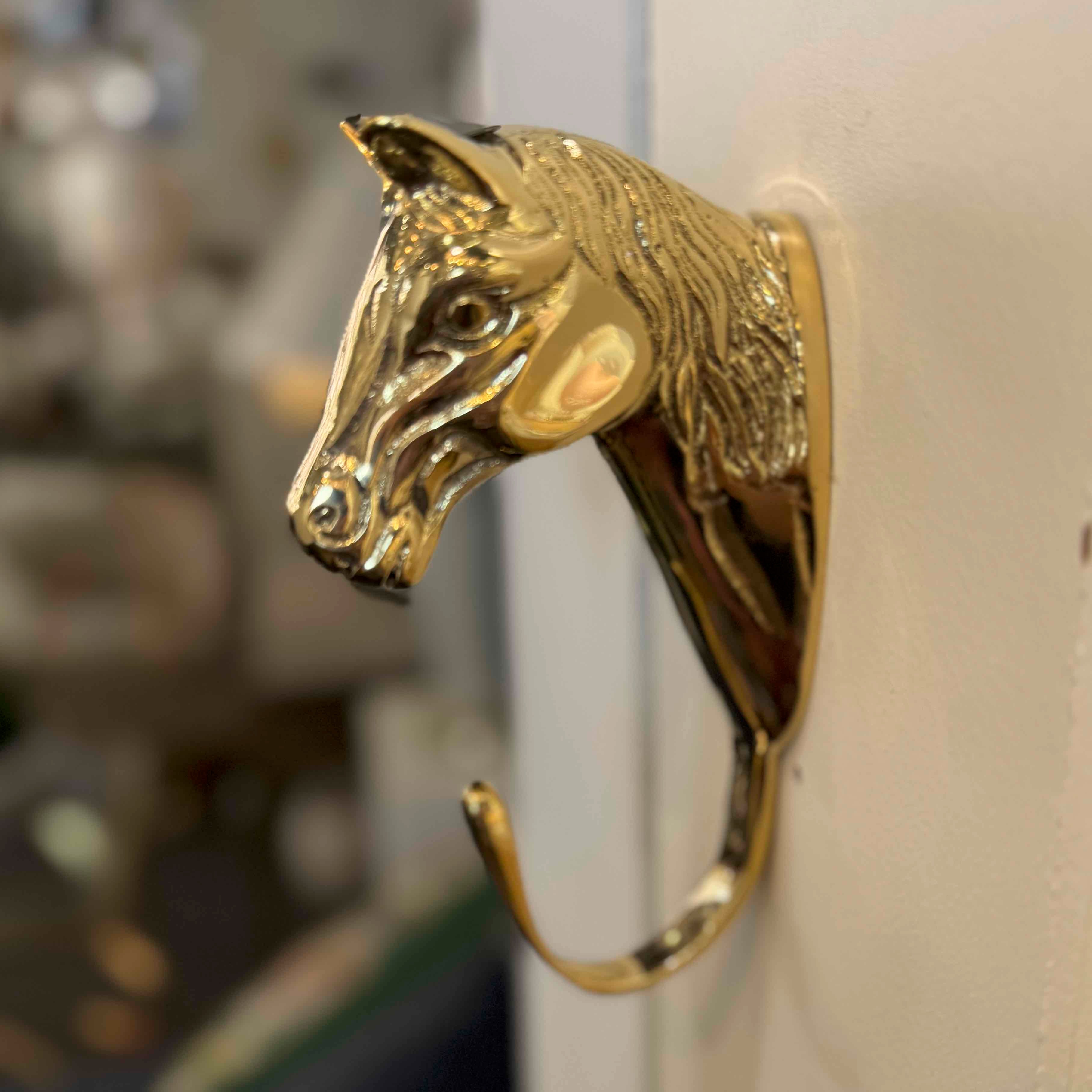 Gold horse head hook on a white wall