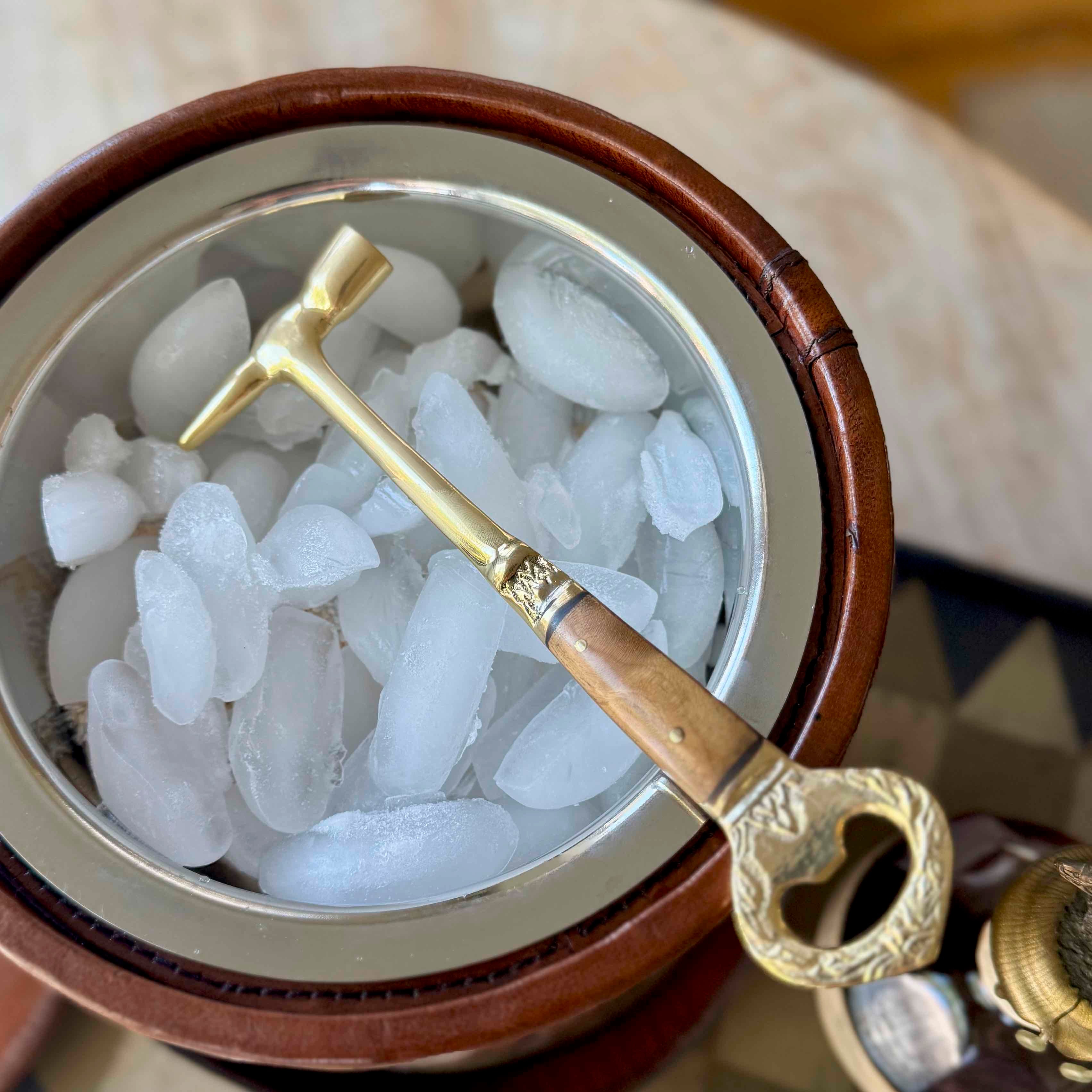 Gold ice pick in a container of ice with a wooden handle
