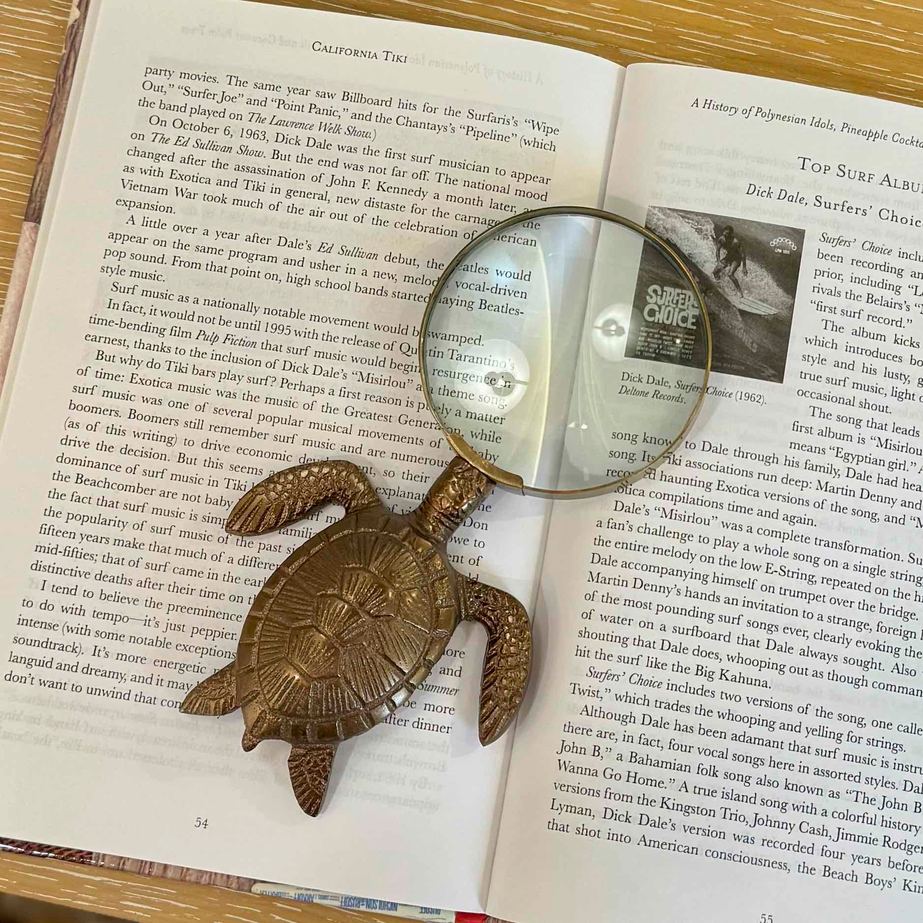 Bronze turtle-shaped bookend on an open book with a magnifying glass.