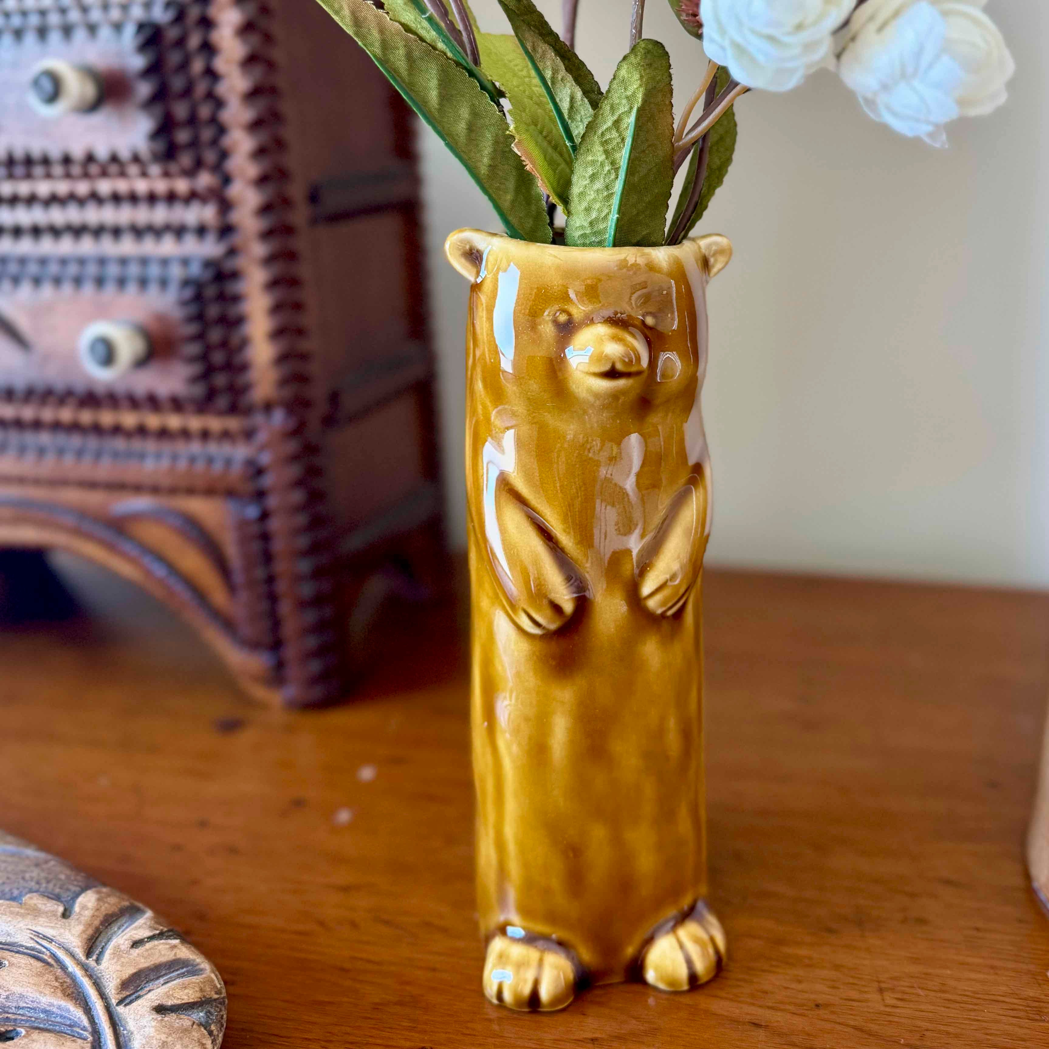 Bear-shaped ceramic vase with flowers on a wooden surface