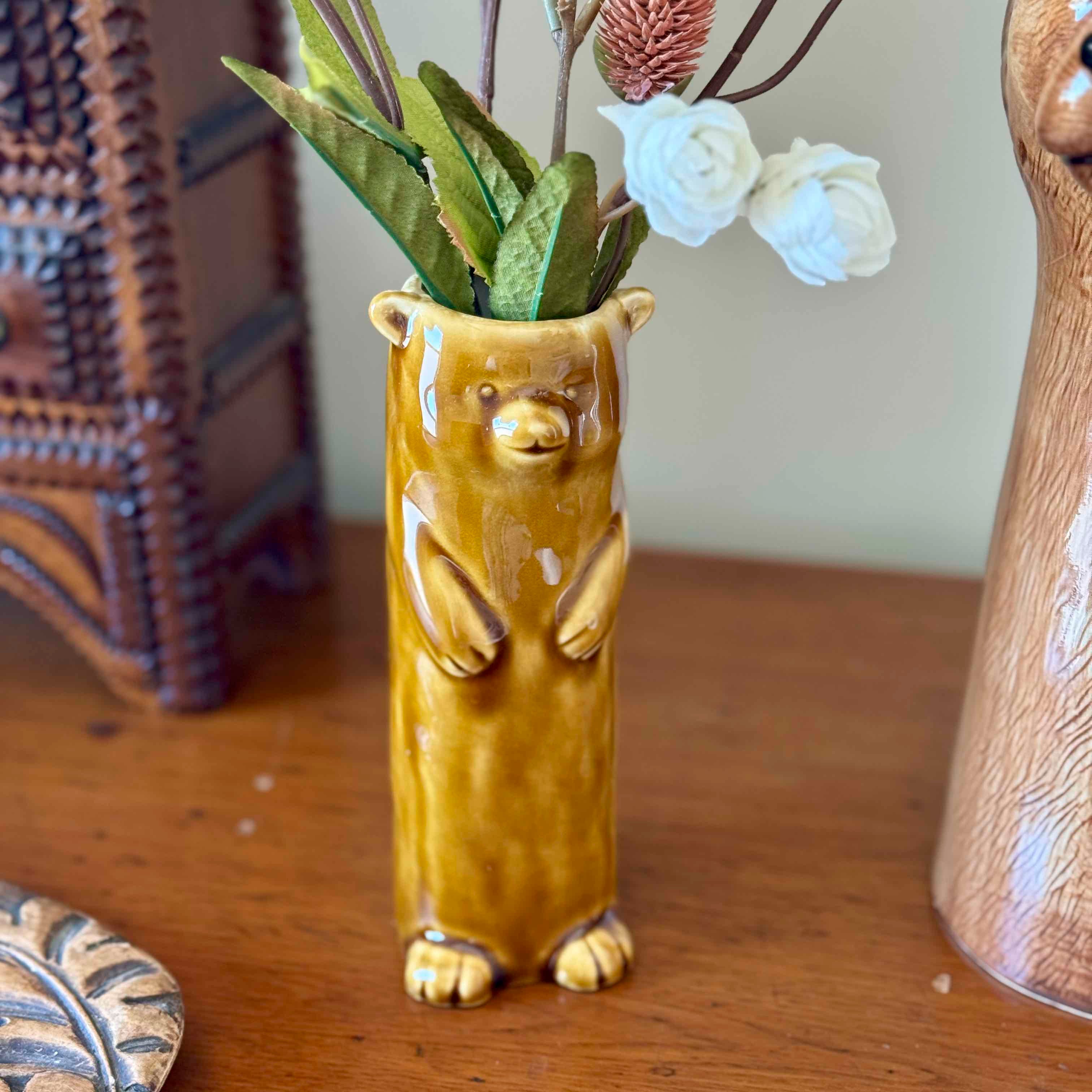 Bear-shaped vase with plants and flowers on a wooden surface