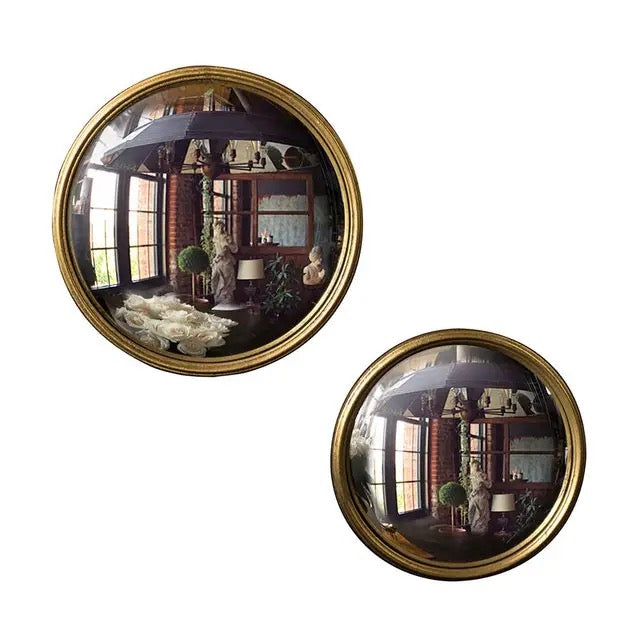 Two round wall mirrors with gold frames reflecting a room interior.