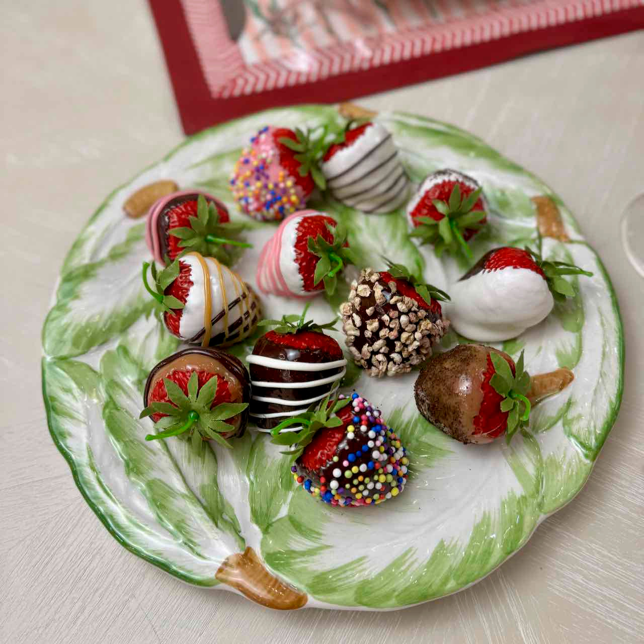 Decorative plate with chocolate-dipped strawberries on a light surface