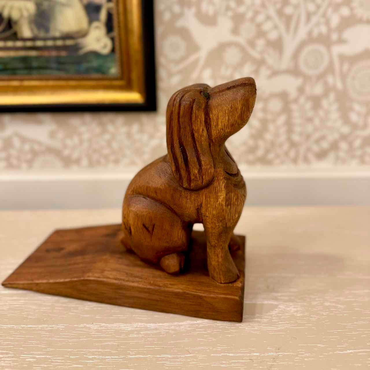 Wooden rabbit sculpture on a stand with a decorative background