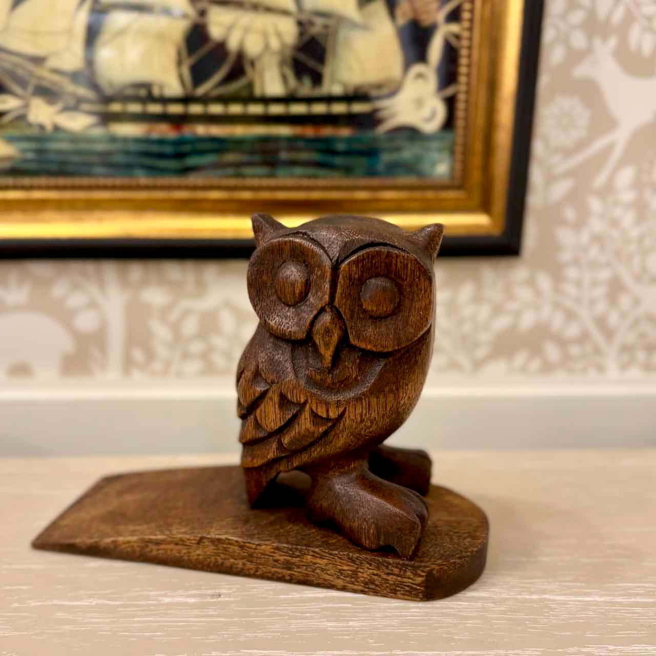 Wooden owl figurine on a surface with a decorative background