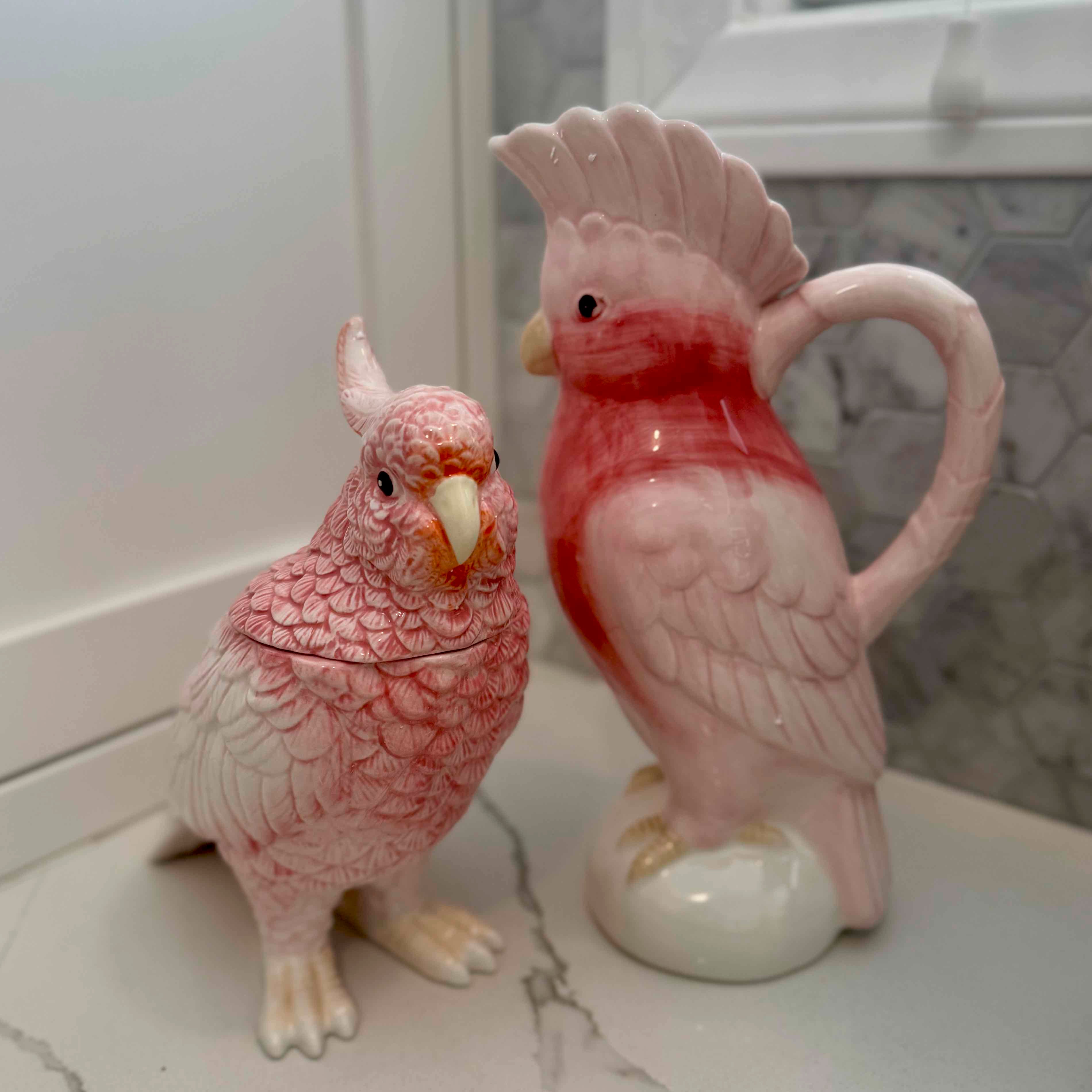 Two ceramic parrot figurines on a marble surface.