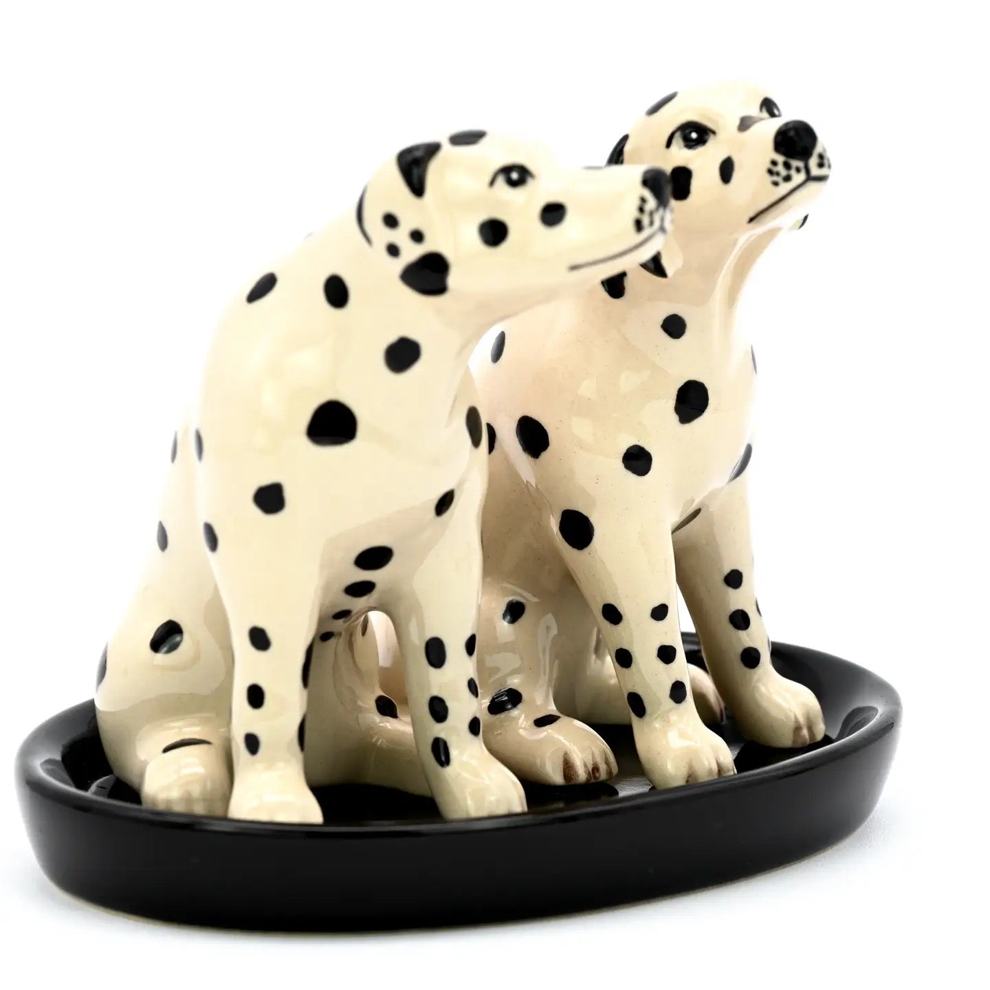 Three Dalmatian dog figurines on a black oval base against a white background