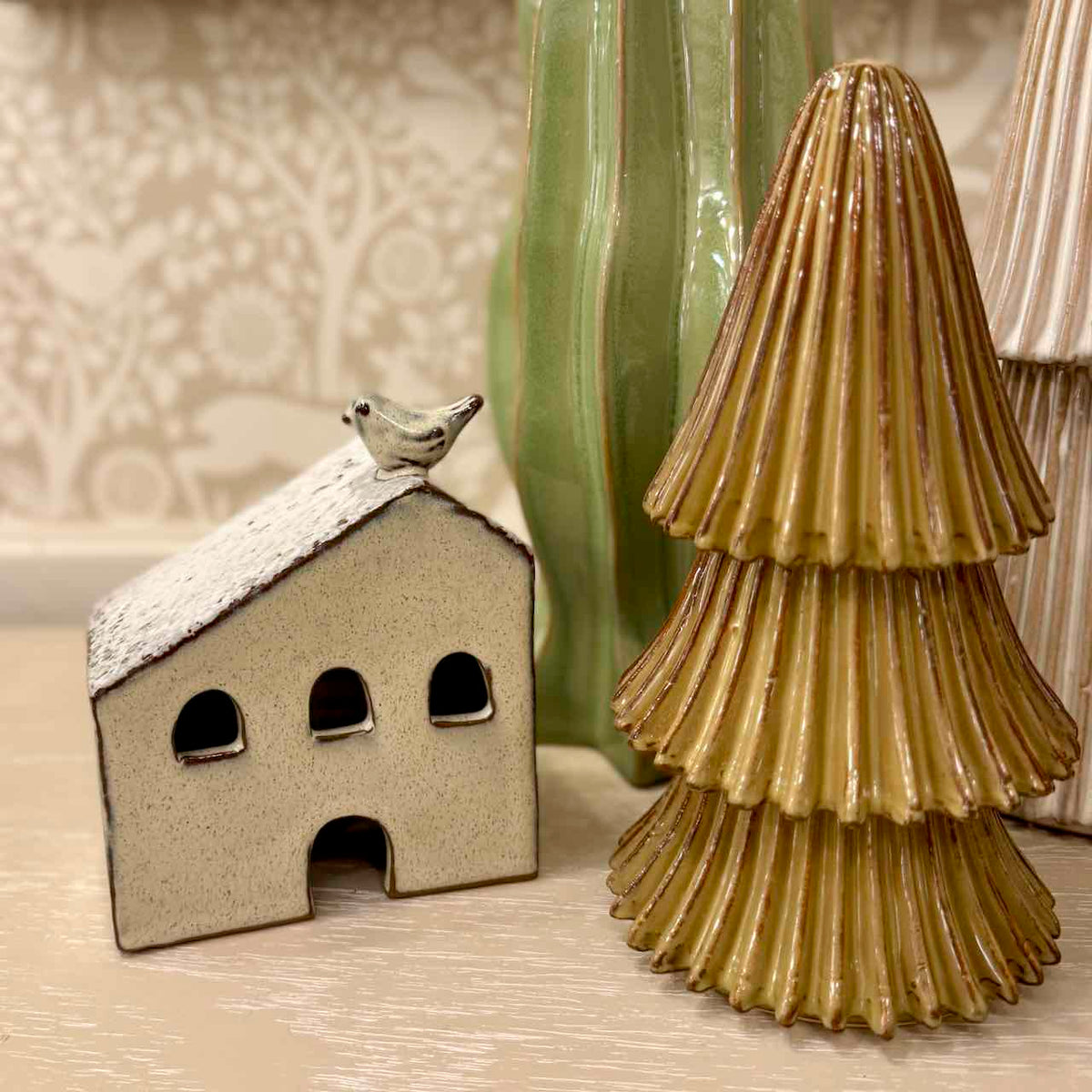Ceramic house with a bird on top and a textured ceramic tree next to it.