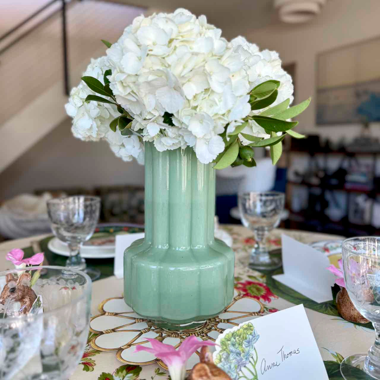Mint green vase with white flowers on a decorated table