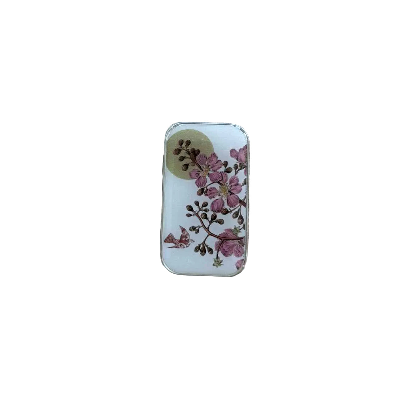 A small rectangular white tin with a floral print of pink blossoms and brown leaves, resting on a light-colored wooden surface.