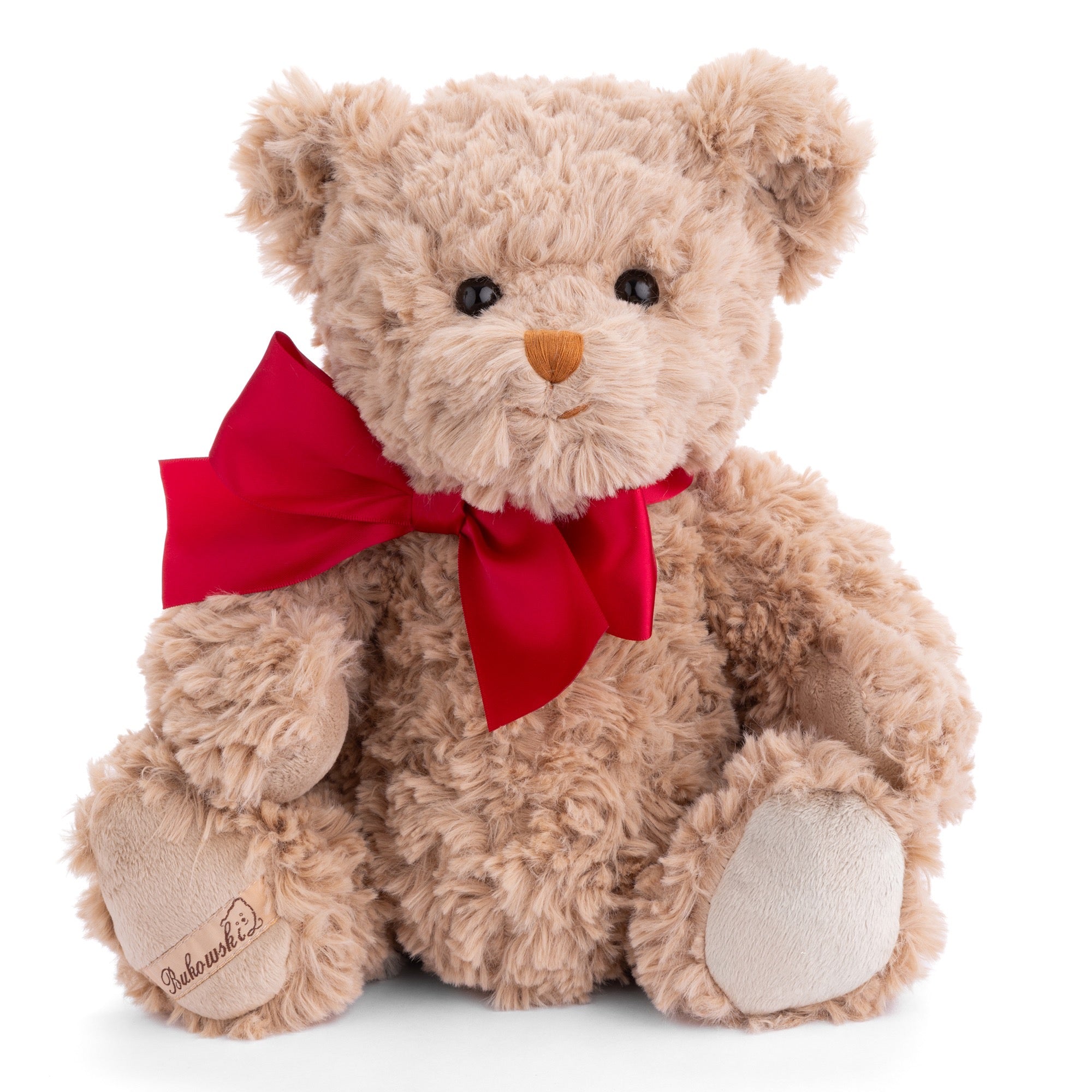 Beige teddy bear with a red bow on a white background