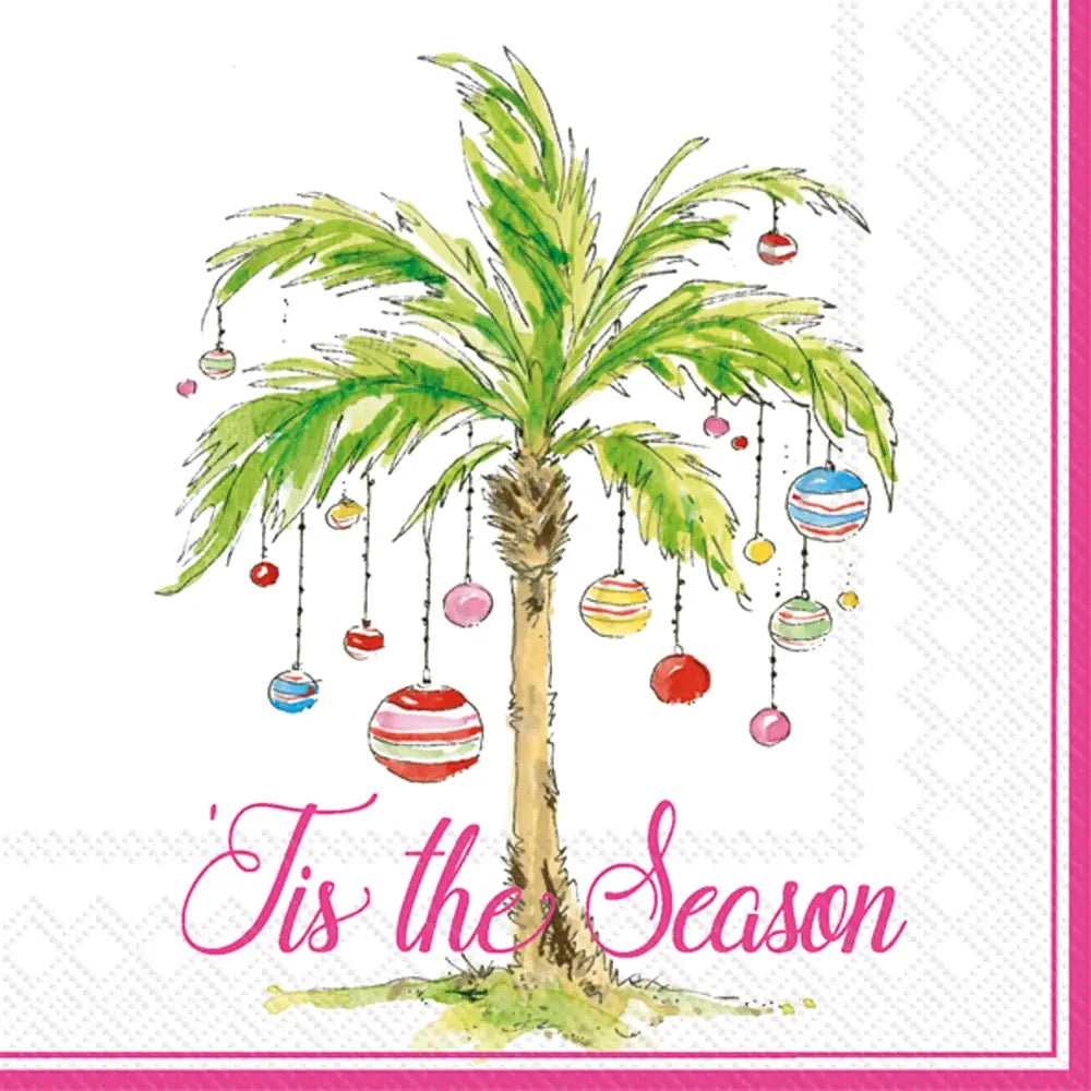 A festive paper napkin or card design featuring a watercolor-style palm tree with hanging striped ornaments and the pink script text “Tis the Season” on a white background with a pink border.