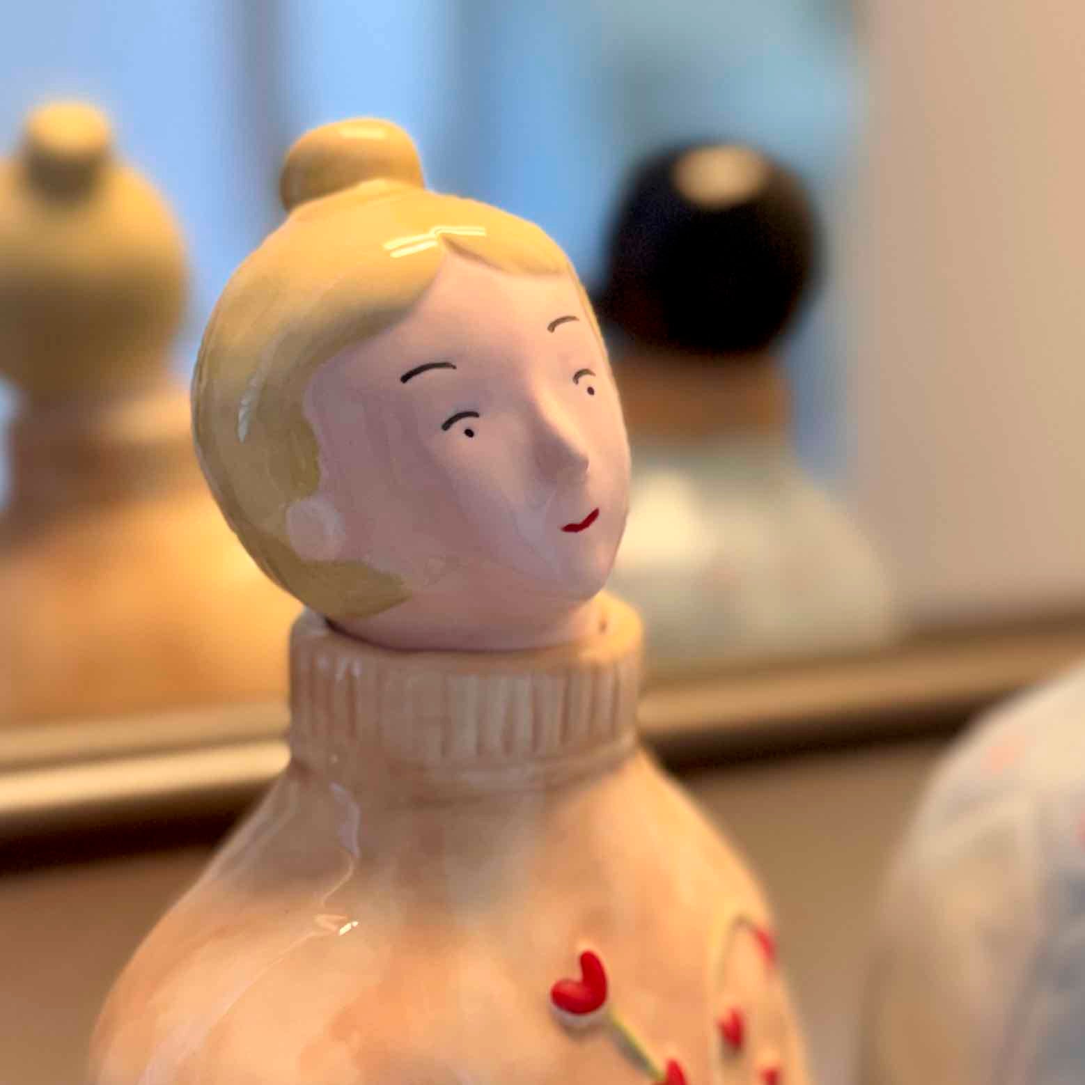 Ceramic figurine of a girl with blonde hair and a white sweater, blurred background