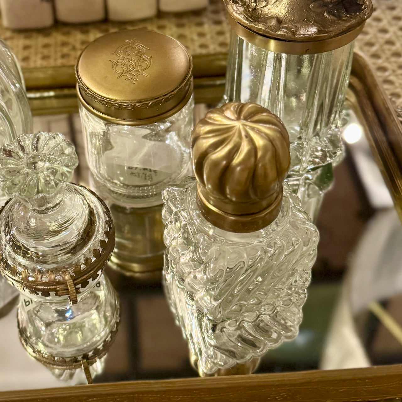 Collection of vintage glass bottles with gold caps on a reflective surface.