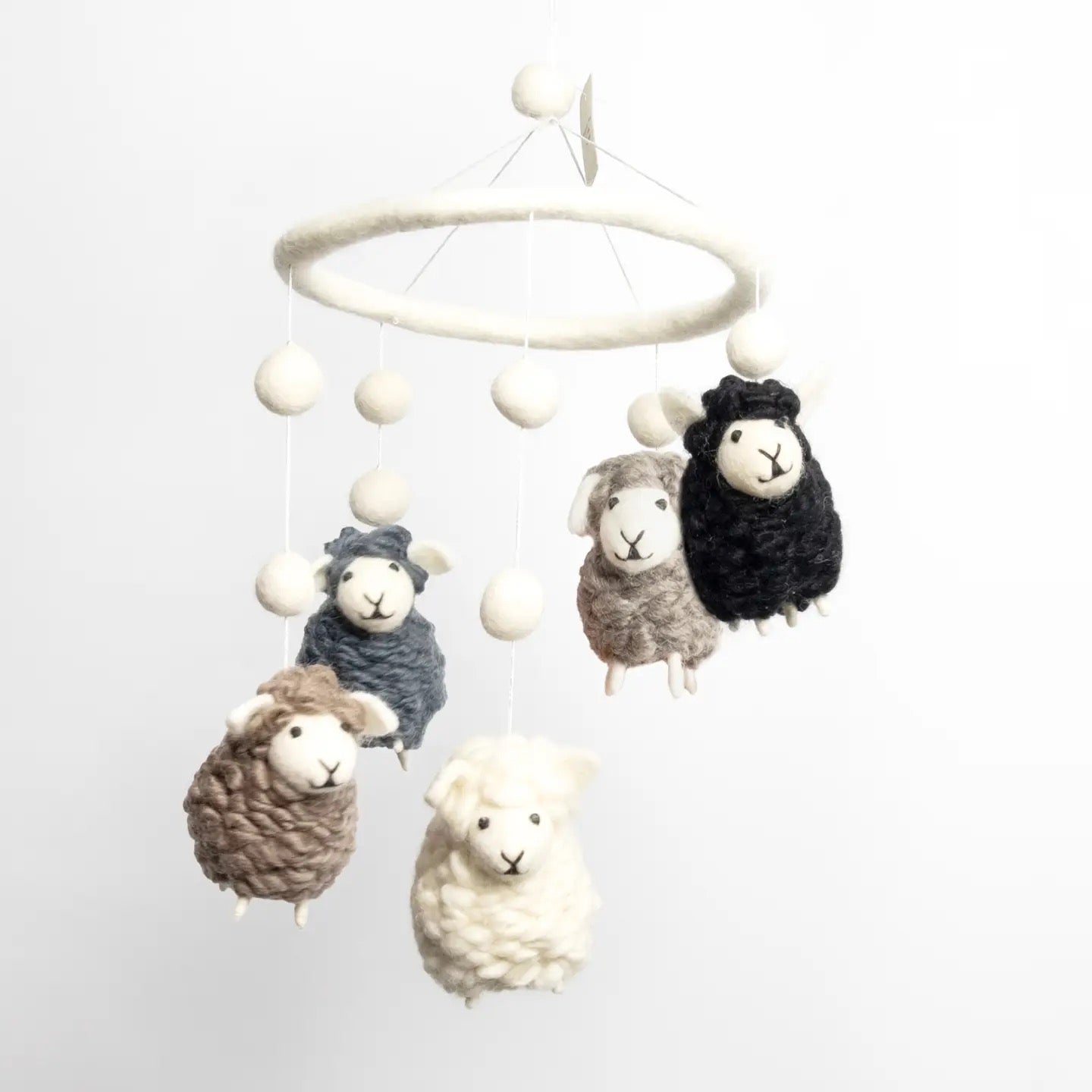 Nursery mobile with sheep hanging from a white circular frame on a light gray background